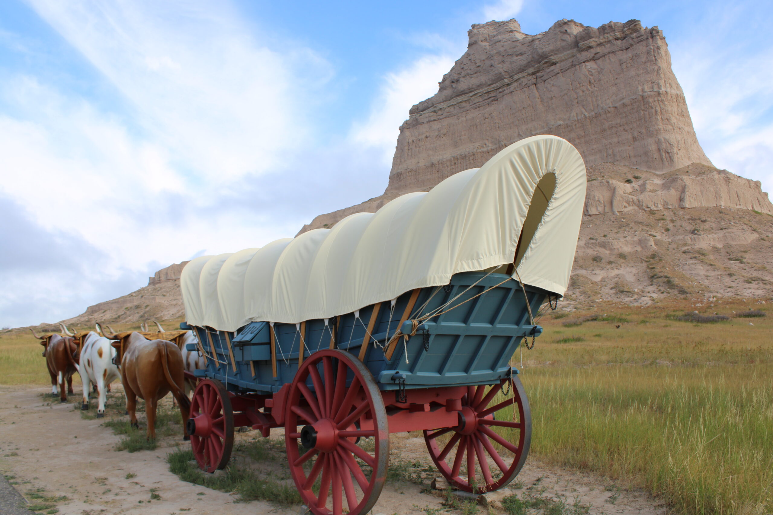 Covered wagon replica in front of Scott's Bluff (large rock bluff)