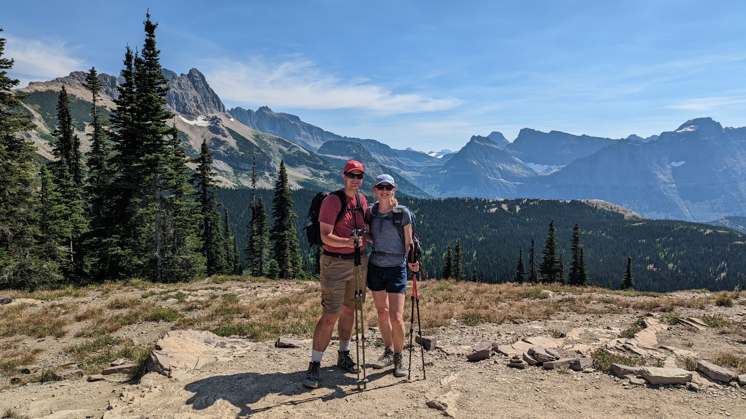 A man and woman stand with mountains in the background at Glacier National Park