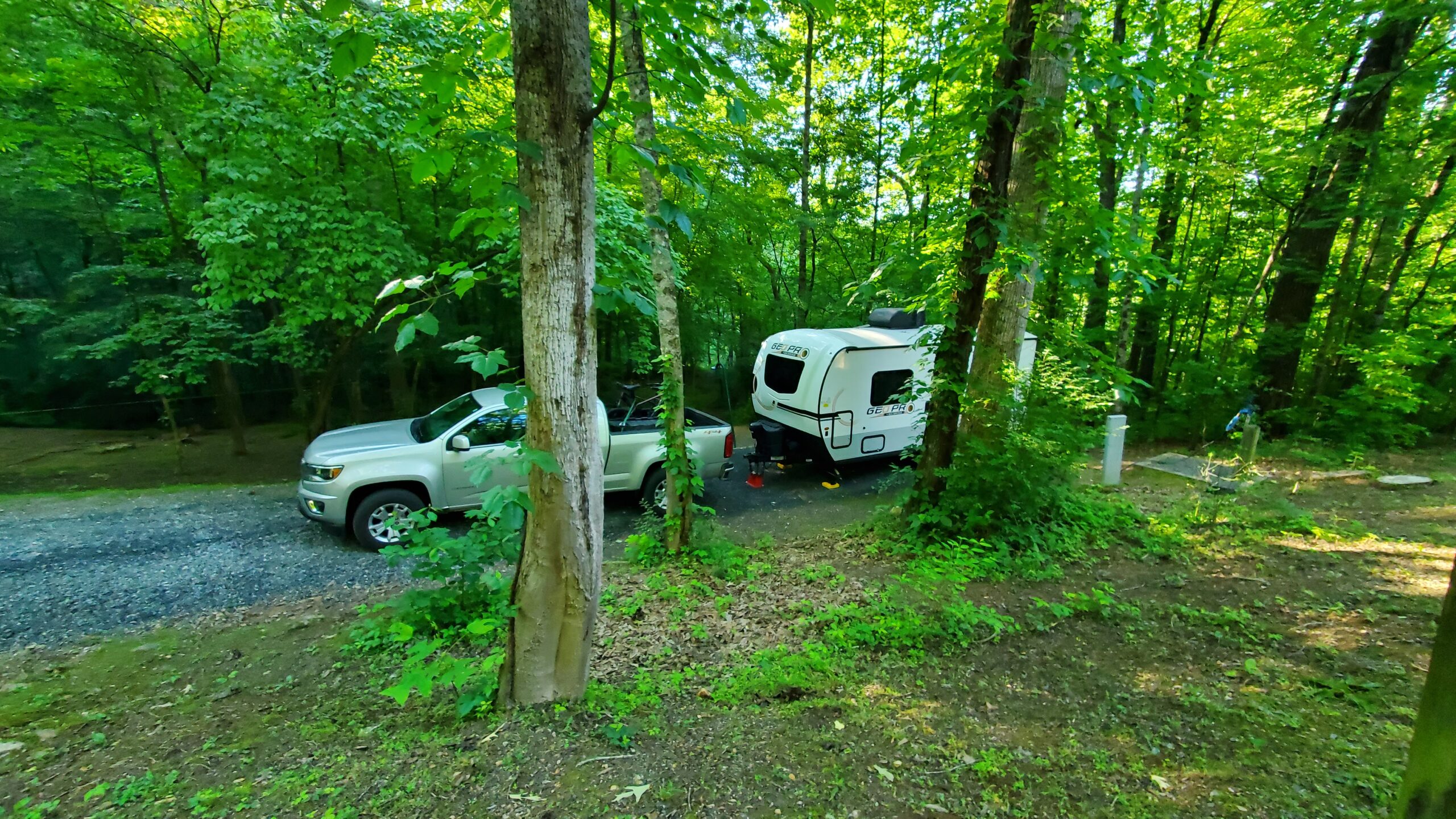 Truck and travel trailer at a campsite behind the trees