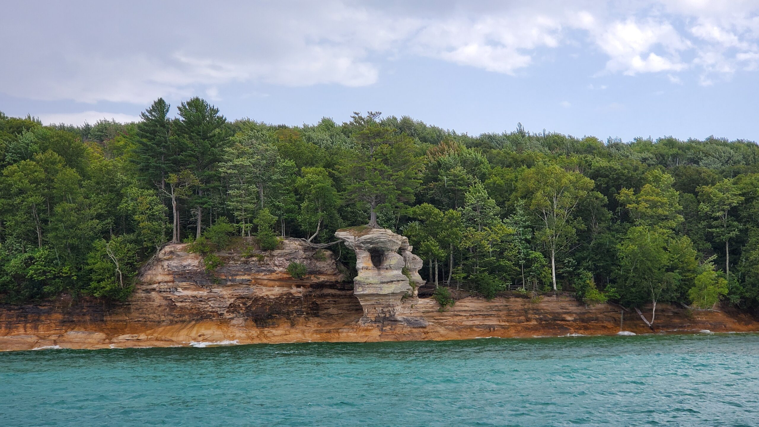 Cliff of Pictured Rocks National Lakeshore with blue Lake Superior and green trees on top