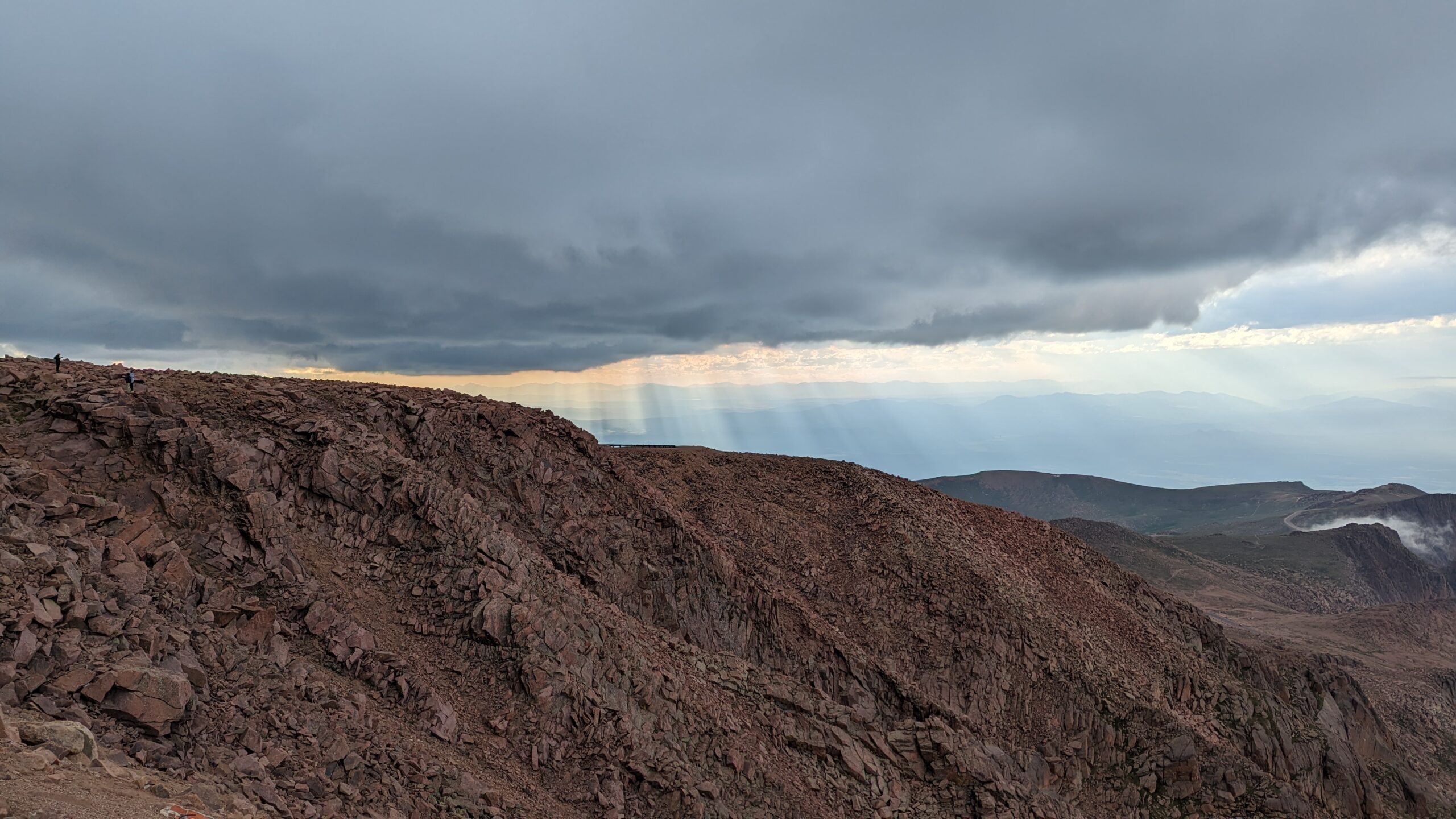 Mountains with dark clouds and sunbeams shining through on the summit of Pikes Peak