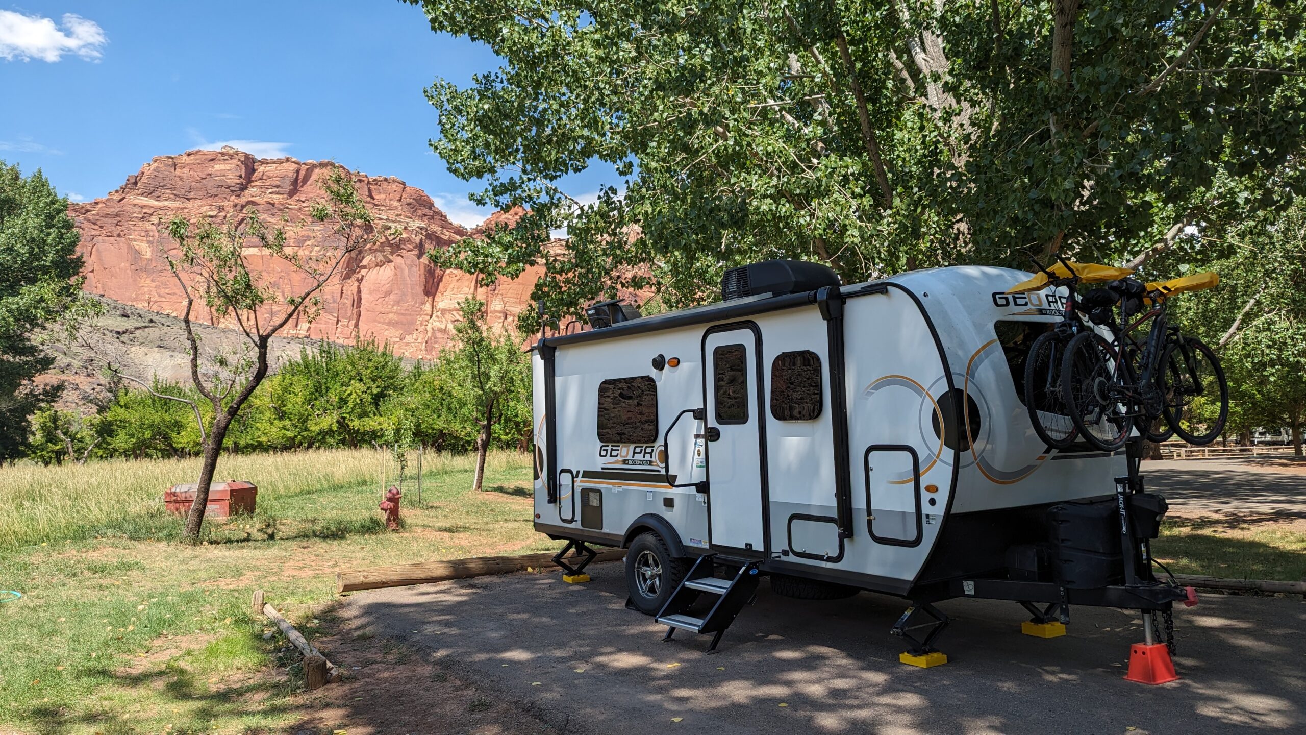 Travel Trailer surrounded by grass and tall red rocks