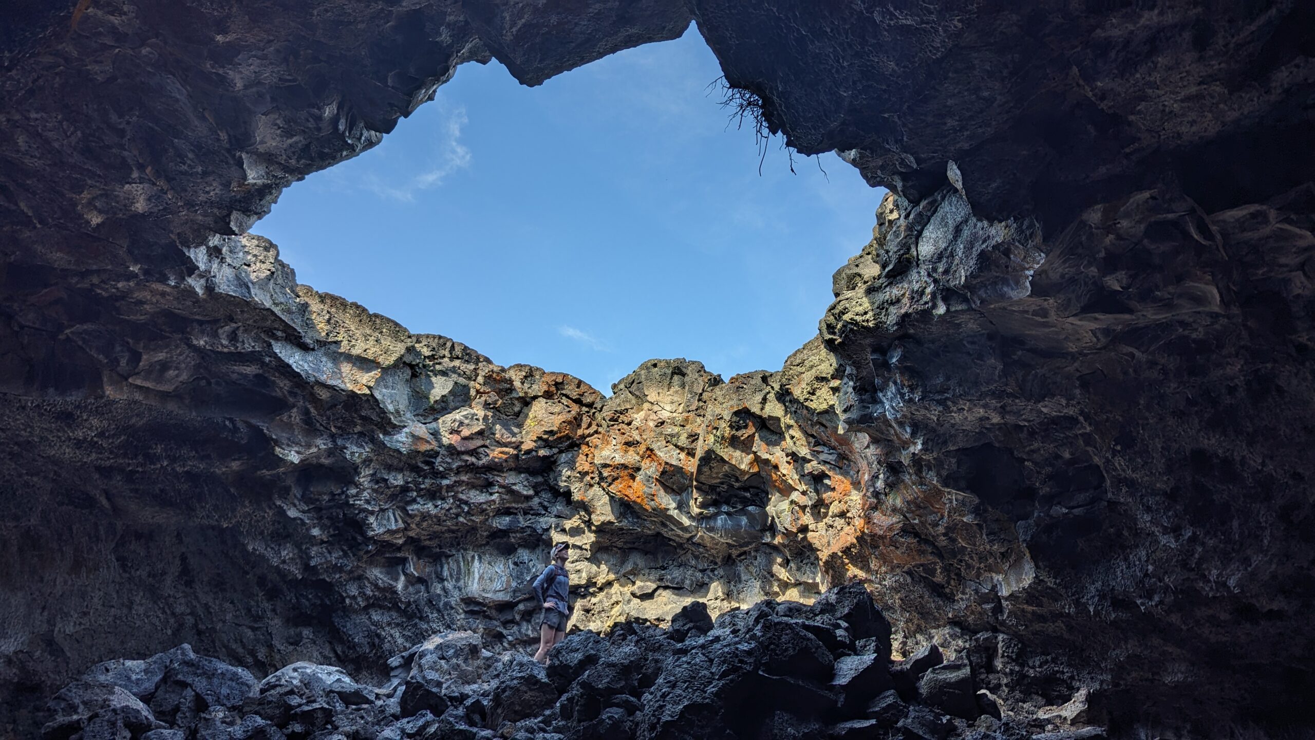 A woman looks up out of a hole in the lava tubes at Craters of the Moon National Monument